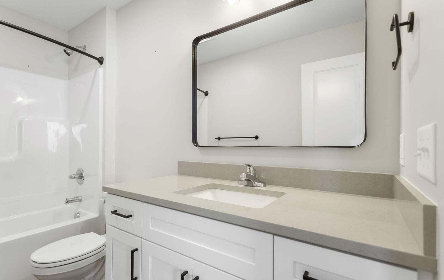 Modern bathroom with white vanity, mirror, and tub shower combination