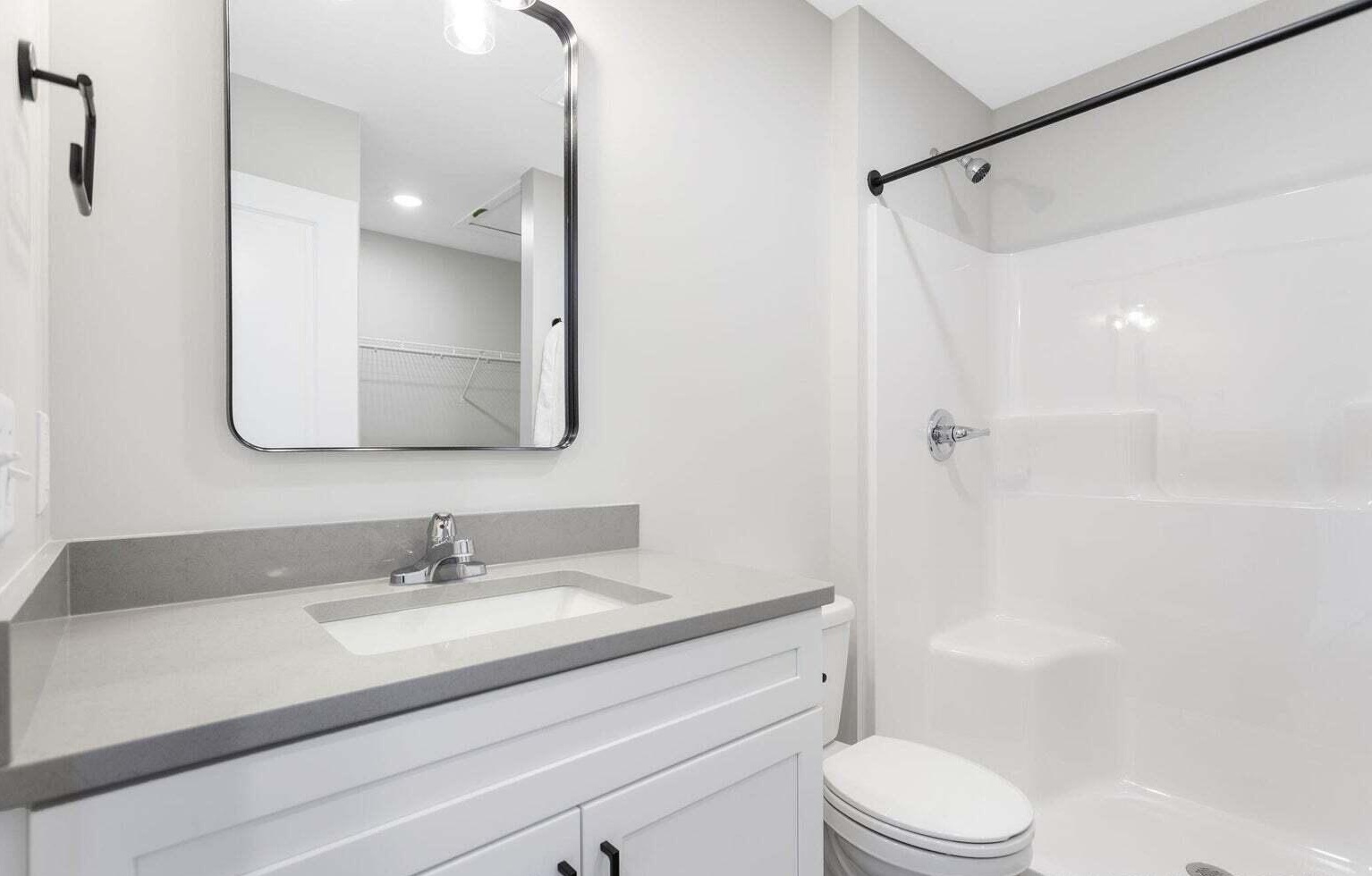 Modern full bathroom with white vanity, large mirror, and tub shower