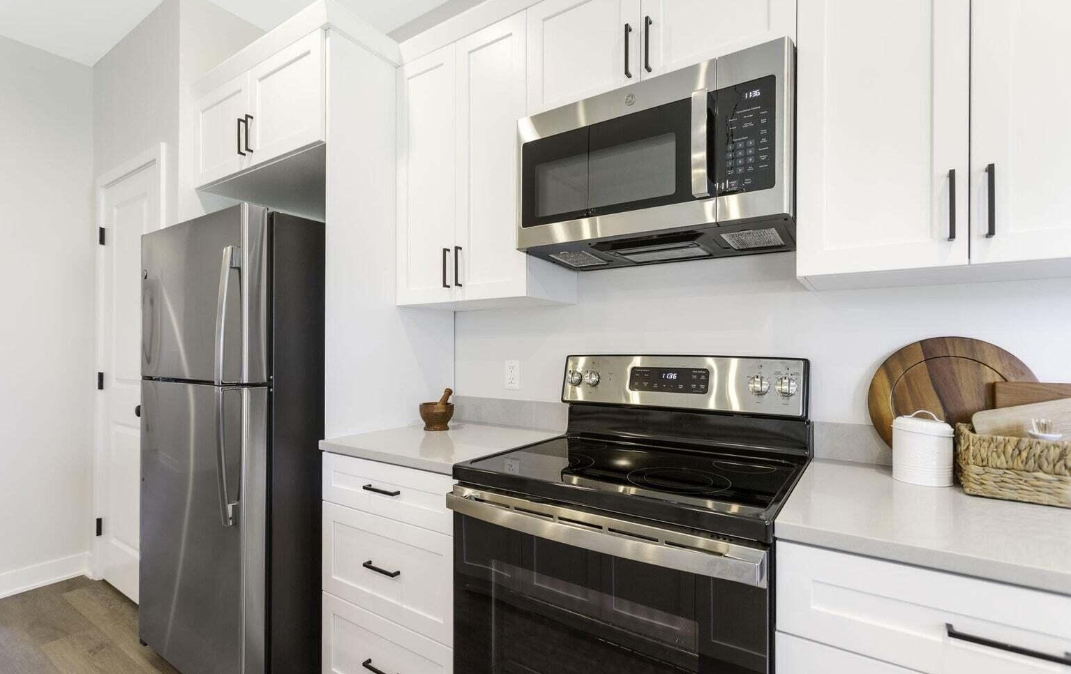 Modern white kitchen with stainless steel refrigerator, range, and microwave