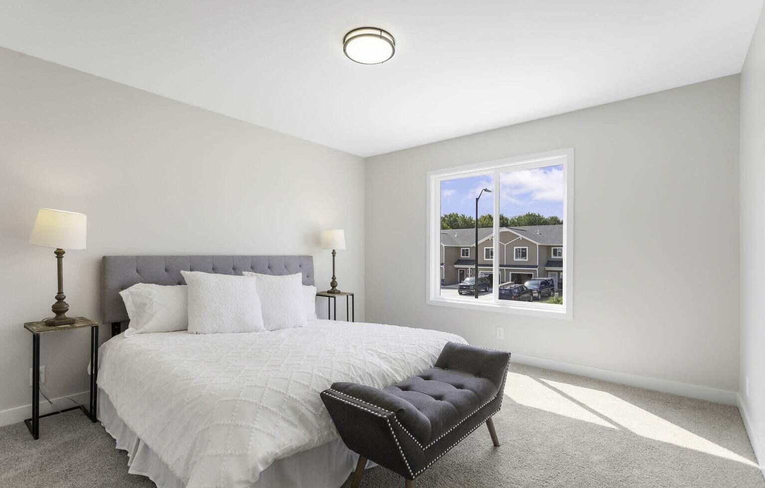 Spacious primary bedroom at Signature Estates with neutral finishes, large window and contemporary furnishings